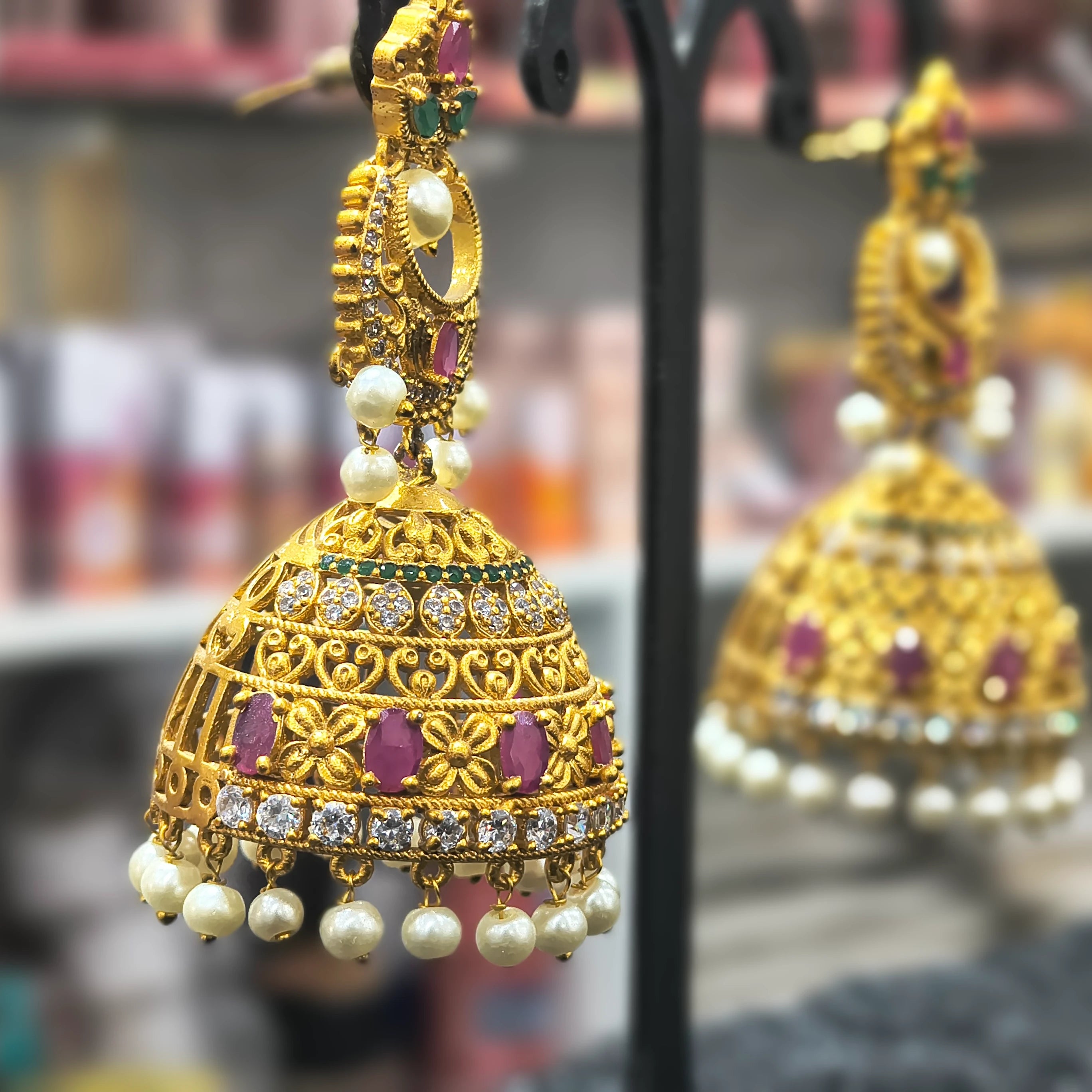 Gold earrings with pearls and gemstones on a blurred background