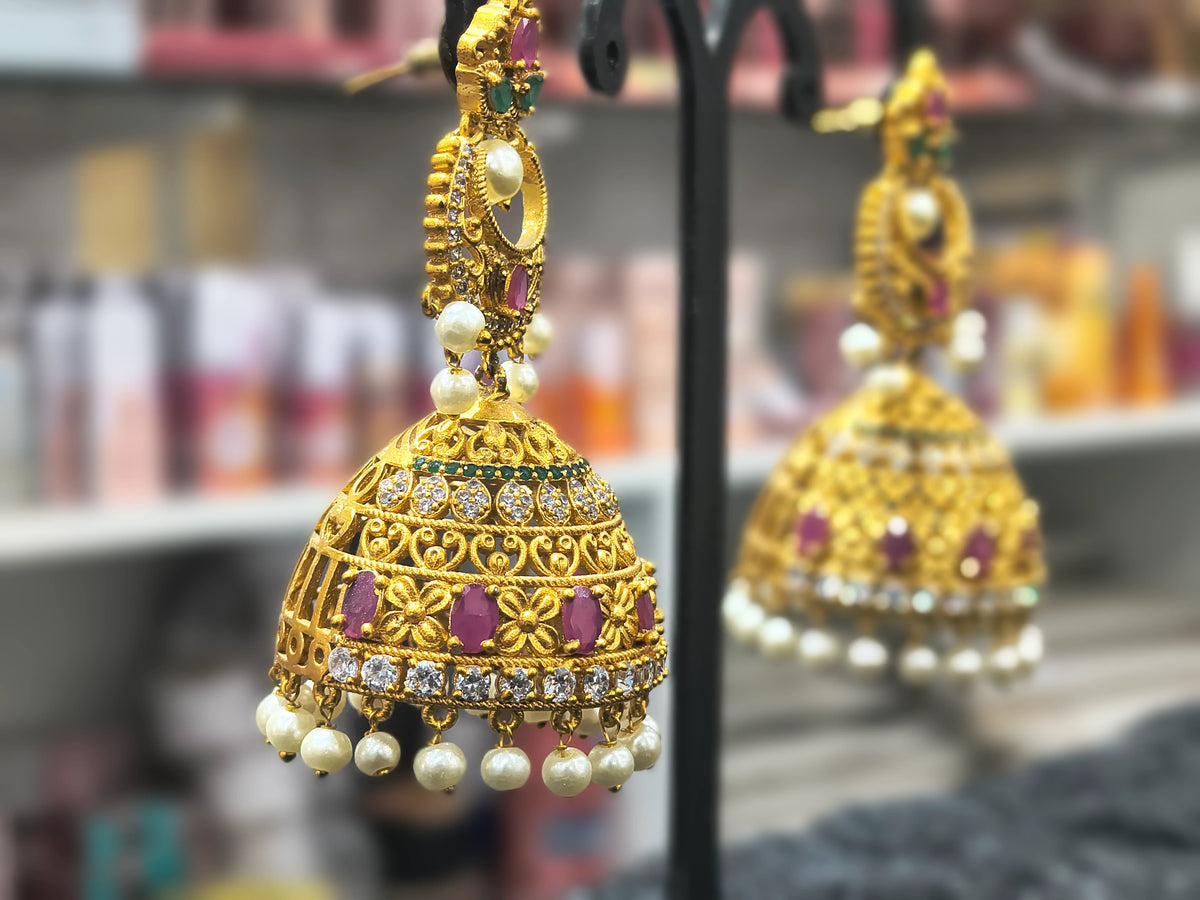 Gold earrings with pearls and gemstones on a blurred background